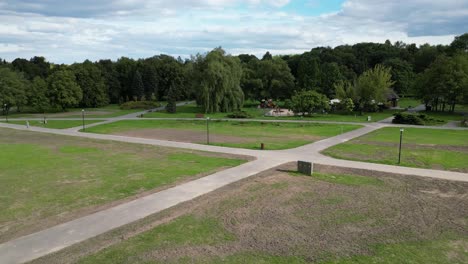 Park-during-a-summer-day-surrounded-by-lush-greenery,-grass-and-trees-under-a-blue-sky