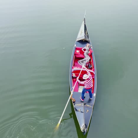 beautiful woman sailing in gondola. gondolier with oar moving boat slowly. gondola floating the calm river in the evening.