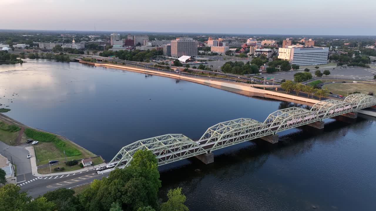 Aerial flyover Morrisville-Trenton Railroad Bridge over Hudson River in Trenton, New Jersey. Sunset time in american town. Wide shot