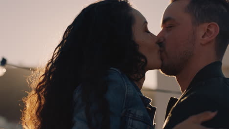 happy-young-couple-kissing-enjoying-rooftop-party-dancing-to-lively-music-sharing-romantic-relationship-at-diverse-social-gathering-at-sunset