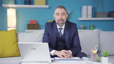 el hombre de negocios de traje trabaja en casa y está satisfecho con la forma en que van las cosas.
