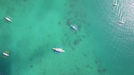 aerial tracking shot of turquoise waters with traditional filipino bangka boats in el nido, palawan, the philippines