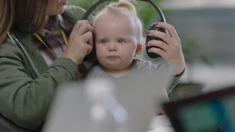 young caucasian business woman mother playing with baby daughter at work playful toddler wearing headphones enjoying loving mom successful motherhood in office workplace