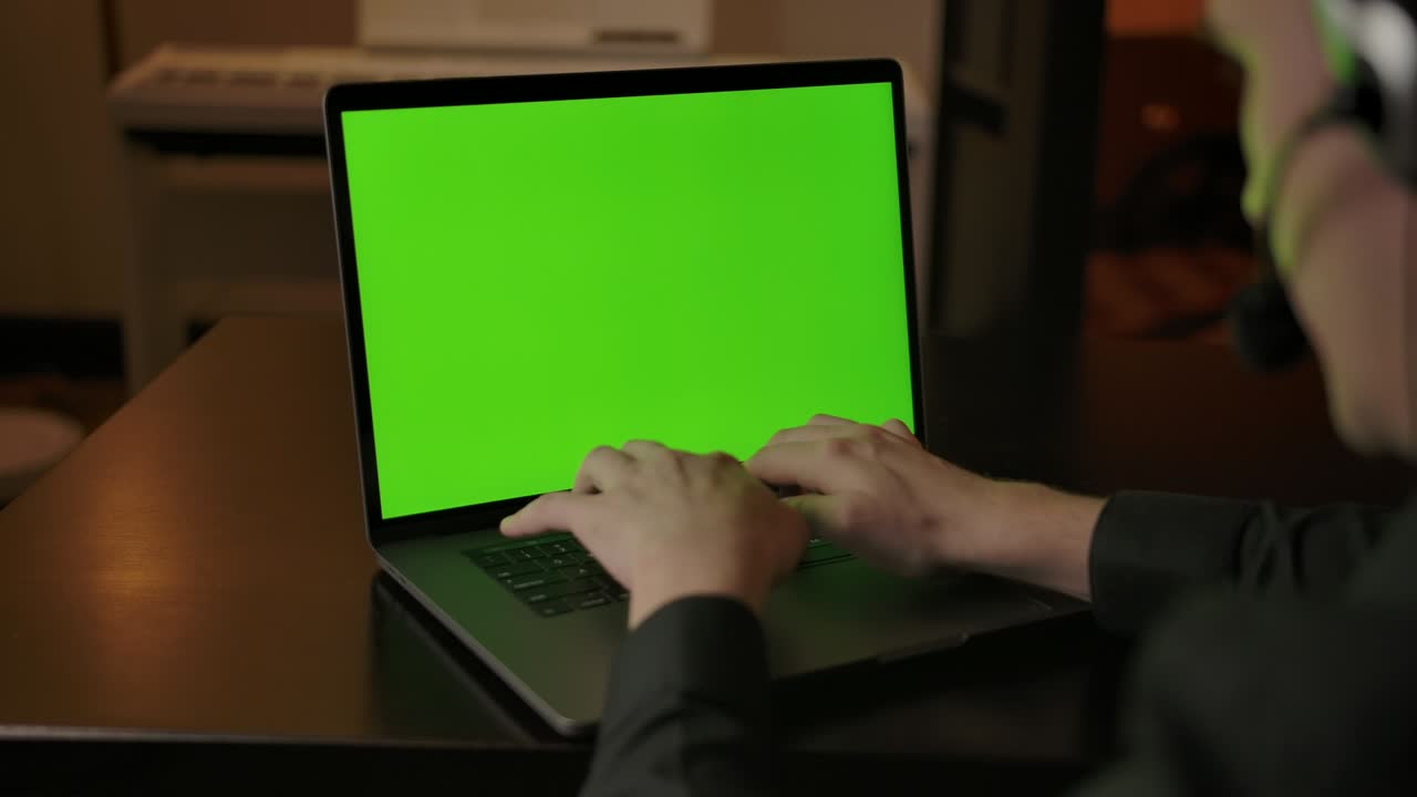 empleado del centro de llamadas en casa hablando con el cliente. portátil de pantalla verde en el escritorio