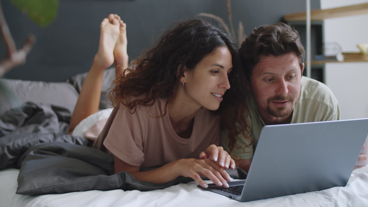 pareja usando la computadora portátil en la cama