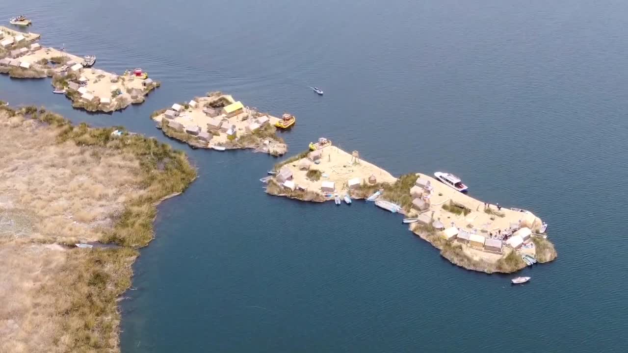 vista aérea de drones en perú volando sobre asentamientos huros en pequeñas islas con pequeños barcos y casas artificiales en el lago titikaka en puno en un día soleado