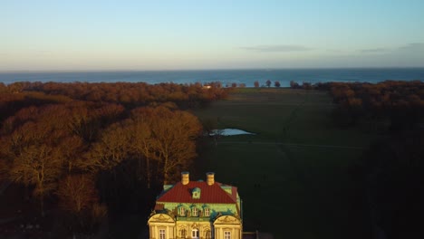 Enthüllen-Ikonisches-Jagdschloss-An-Einem-Sonnigen-Abend-In-Der-Dänischen-Landschaft,-Luftbild