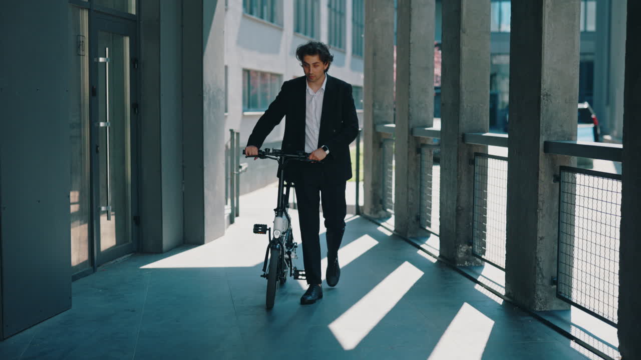 Businessman walking with a folding bicycle in a modern building corridor