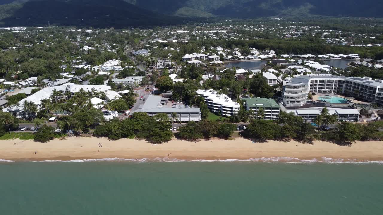 4K drone shot flying towards a beautiful sandy beach and a small seaside town with luxury resorts in Australia