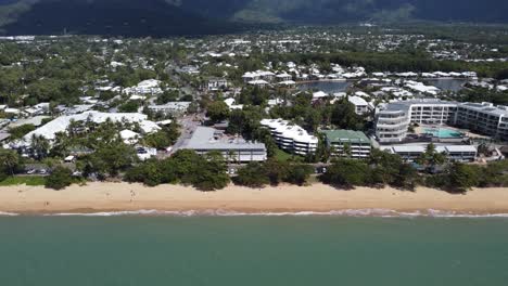 4k drone shot flying towards a beautiful sandy beach and a small seaside town with luxury resorts in australia