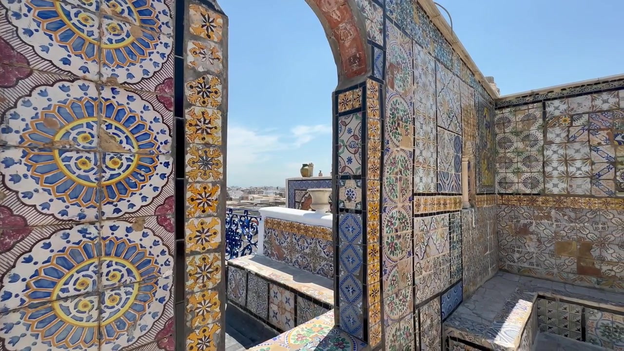 Panoramica a destra di piastrelle che rivestono un arco sul tetto e panchine a Tunisi, Tunisia.