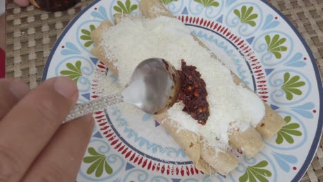 top down shot hands putting sauce on taquitos (taco dorado) on a plate, indoor