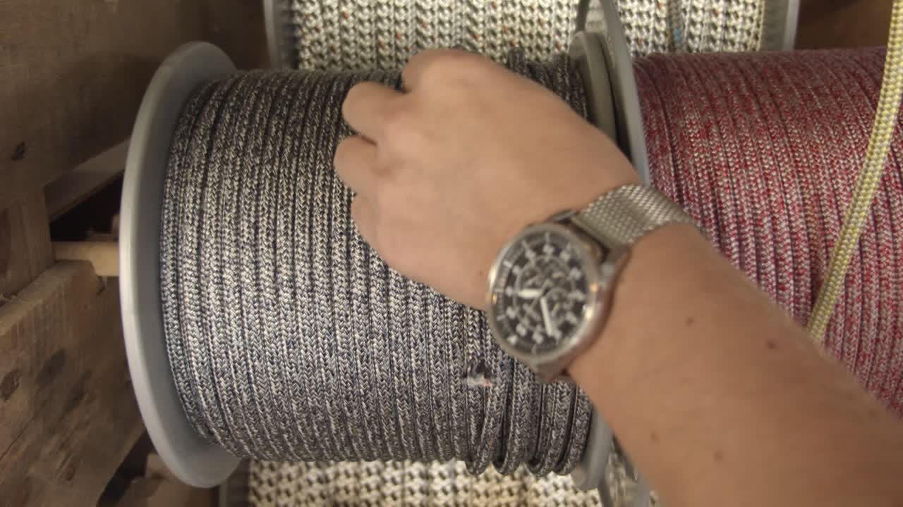 artesano eligiendo cuerda de color plata para hacer una nueva pulsera, vista de cerca