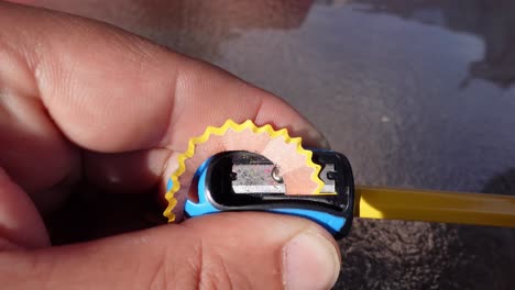 sharpening a pencil with a blue sharpener, close up