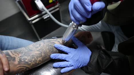 maestro del tatuaje quitando el tatuaje en el brazo del cliente