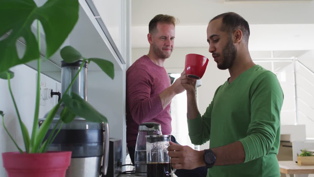 pareja de hombres homosexuales multiétnicos bebiendo café en la cocina