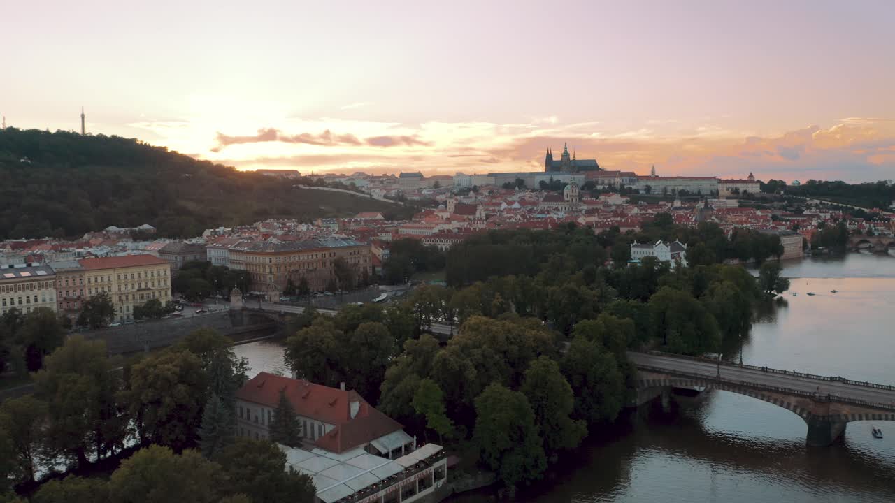 Droonikuva Prahasta, linnasta ja Vltava-joesta auringonlaskun aikaan, elokuvamainen avauskuva