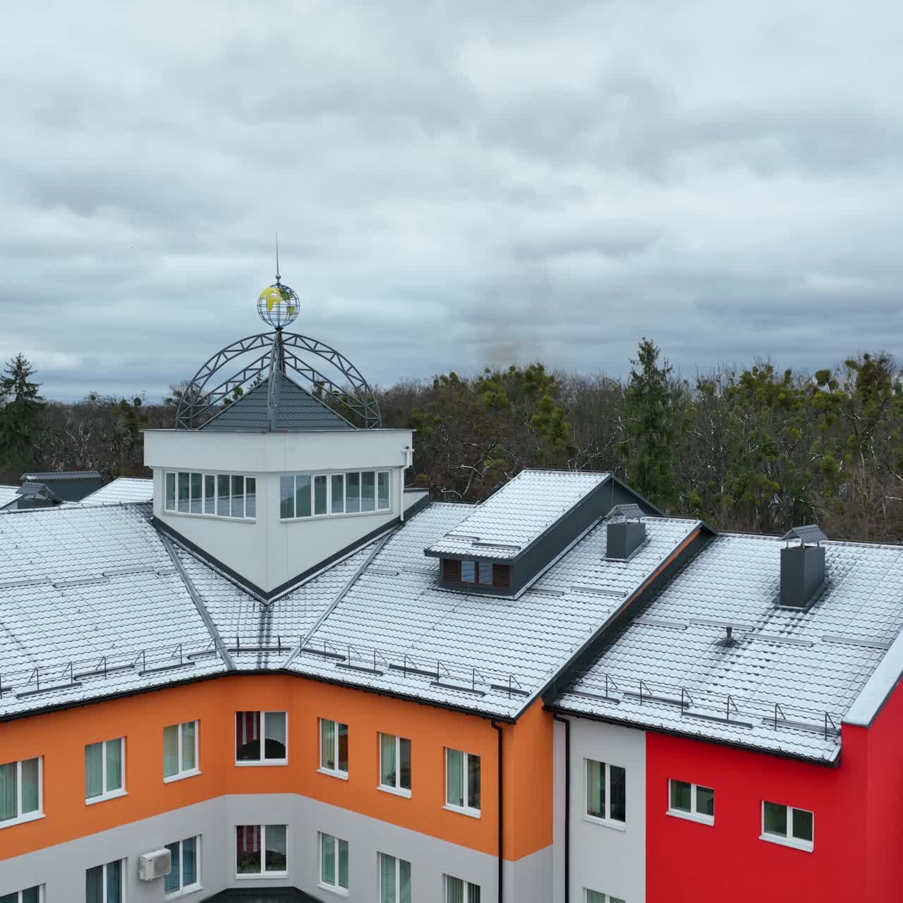 Newly-built bright building in the new residential area. Flight above the three-storied house. Winter park and cloudy sky at the backdrop
