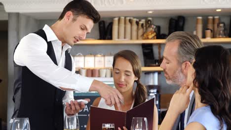 waiter suggesting the menu to three people