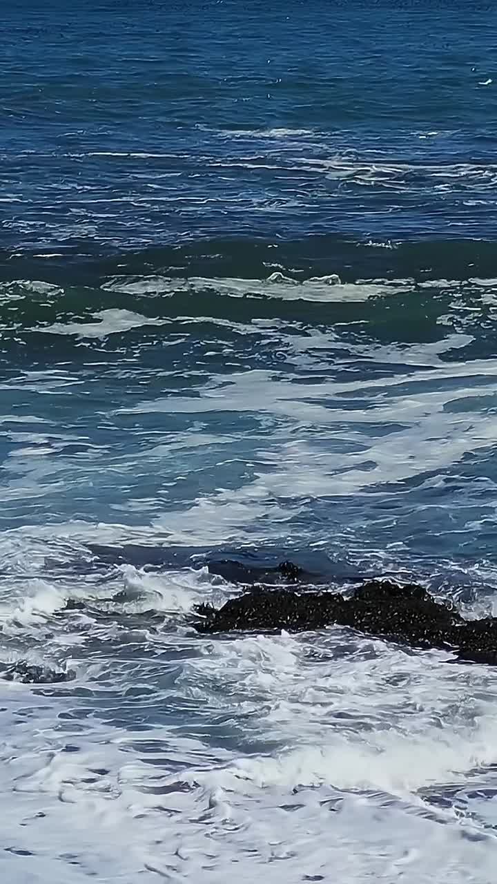 Le onde si infrangono sulla riva di una spiaggia in Cile durante una giornata di sole.