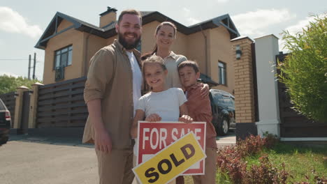 portrait of family posing before new house