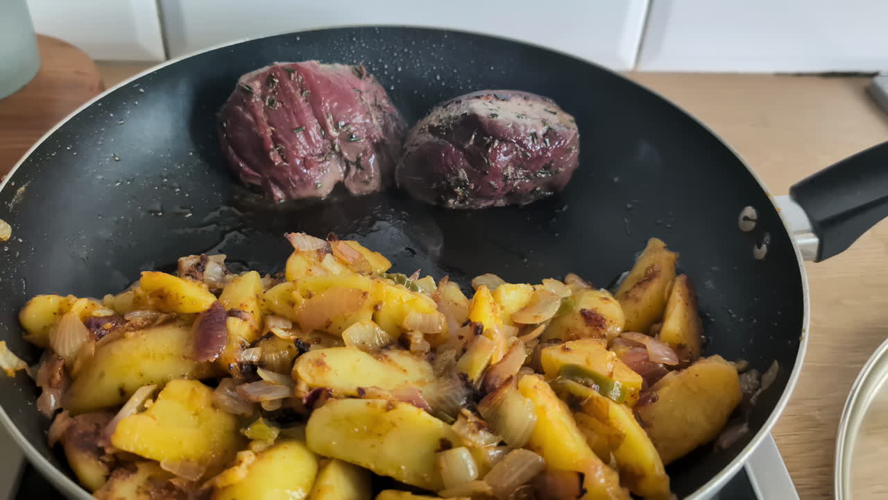 dos deliciosas porciones de carne cocinadas en una sartén en casa, con patatas cortadas y sazonadas