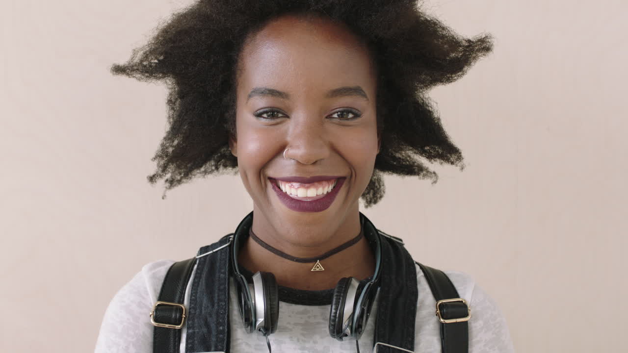 retrato de una mujer afroamericana riendo feliz afro de moda con auriculares