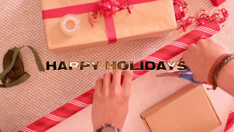 animation of happy holidays text over caucasian man wrapping christmas presents