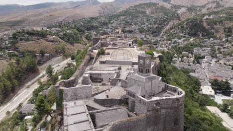 aerial view of tourists visiting gjirokaster fortification on hilltop, scenic clock tower, albania