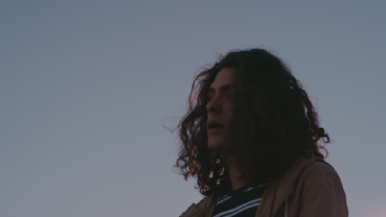 lonely young caucasian hipster man drinking alcohol on rooftop looking unhappy in urban city depression concept