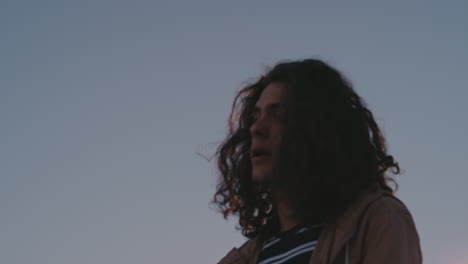 lonely young caucasian hipster man drinking alcohol on rooftop looking unhappy in urban city depression concept