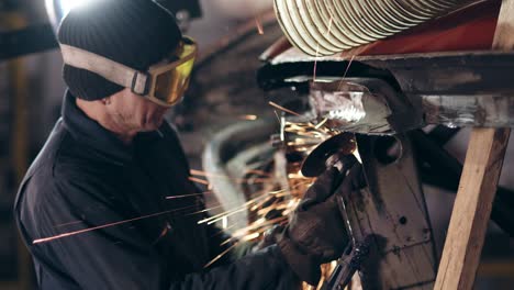 workman with protective eyewear is grinding metal construction with circular saw