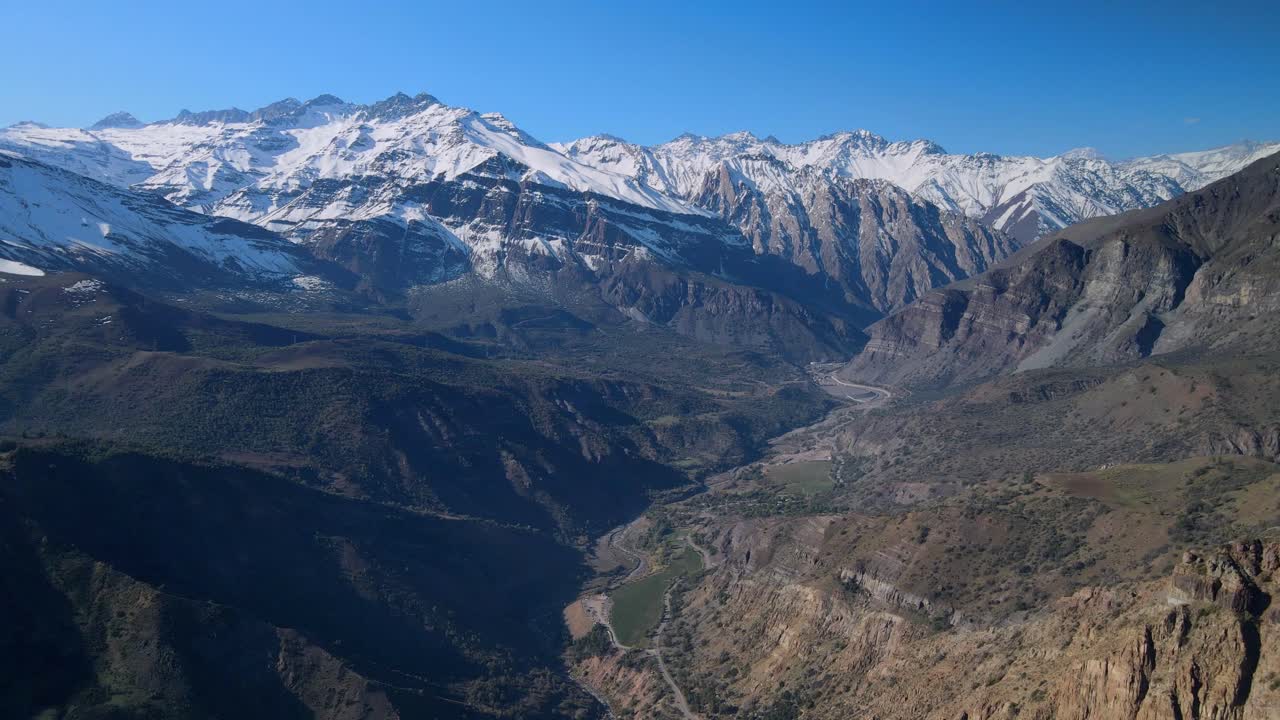 Aerial view of snow capped mountain range above deep valley with ridges