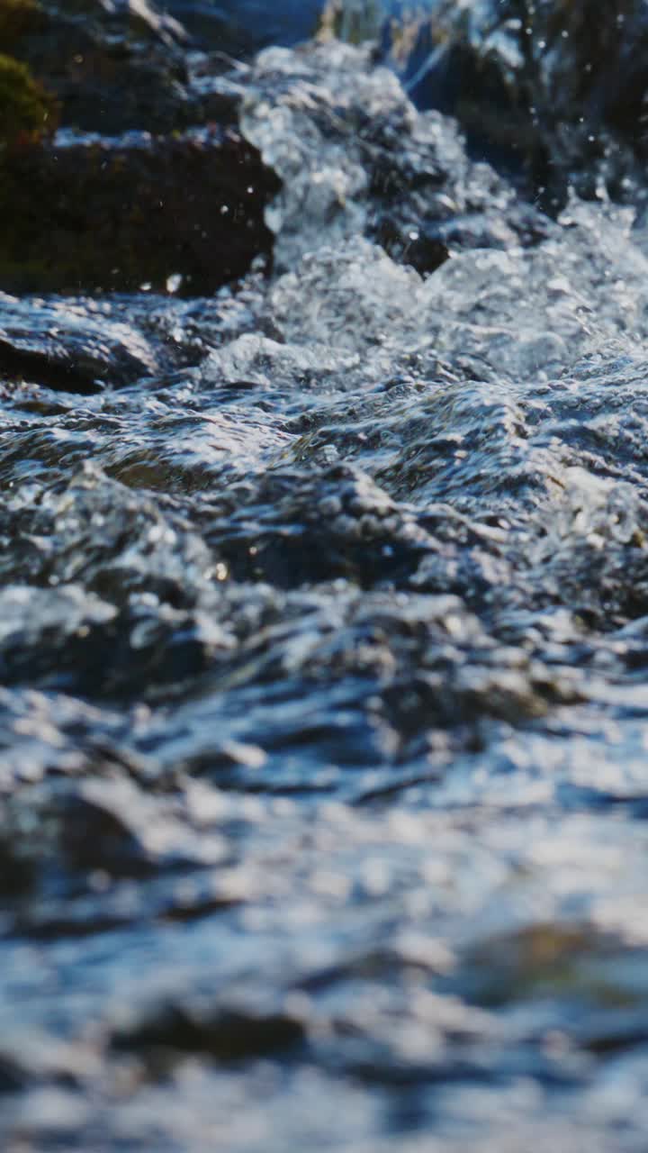Primo piano di acqua limpida che scorre sulle rocce in un ruscello