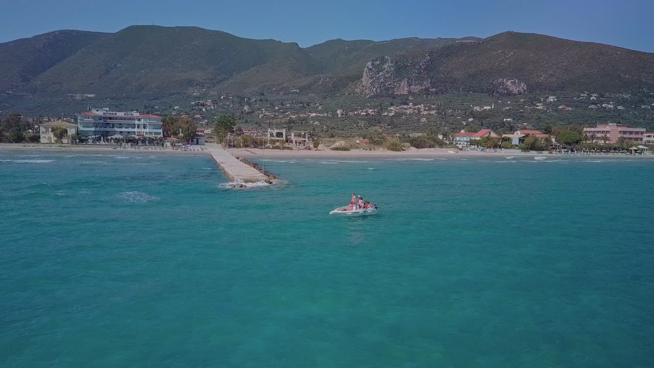 Aerial orbits small boat near pier in beautiful blue Mediterranean Sea