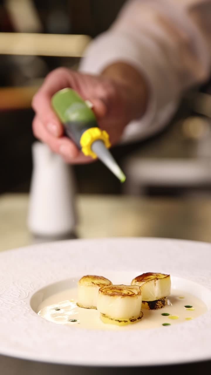 Chef plating scallops with sauce