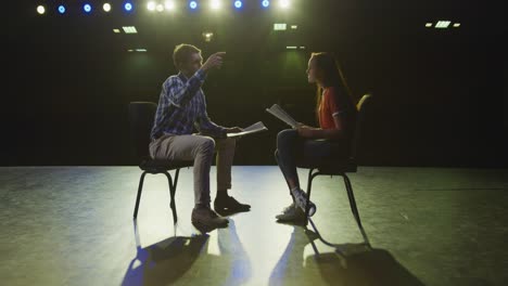 estudiante preparándose antes de una actuación con su maestro de secundaria en un teatro de la escuela vacío