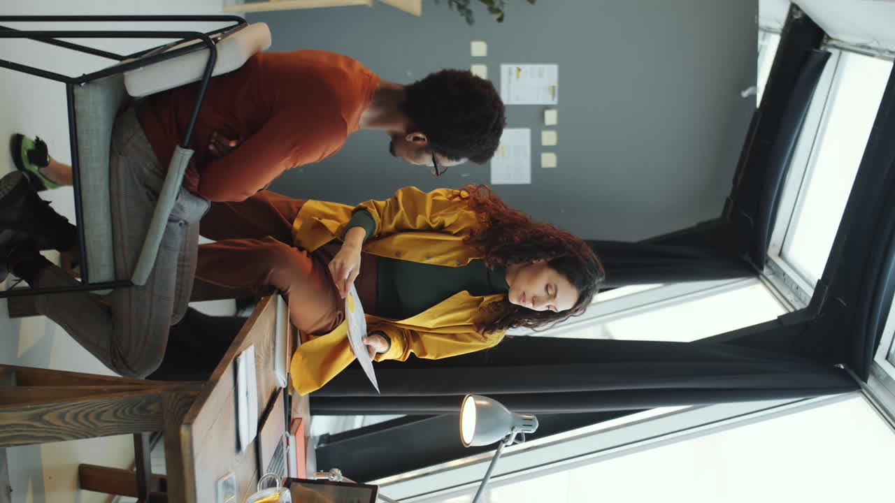 다민족 동료 들 이 옥상 사무실 에서 문서 를 논의 하고 있다