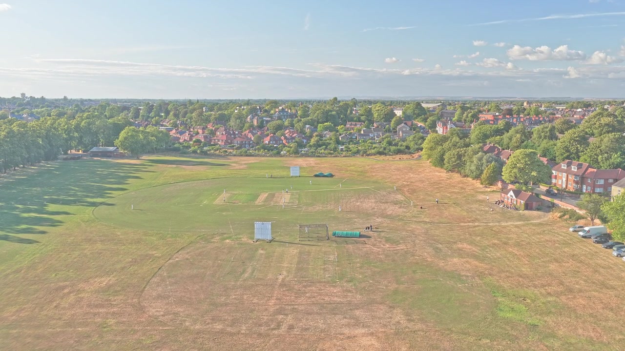 Knavesmire racecourse grounds extend toward tree-lined residential districts in York, North Yorkshire, England, United Kingdom, Europe, drone forward flyover