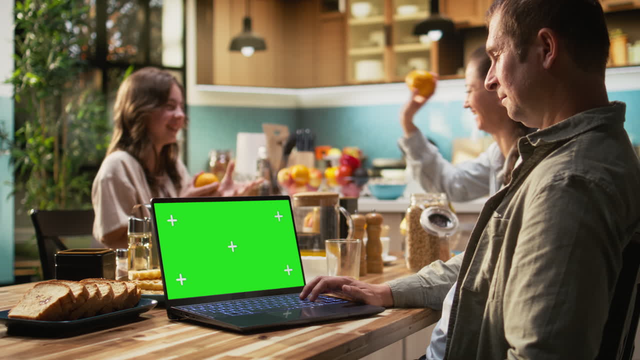 Green screen on pc with family serving breakfast in rustic kitchen