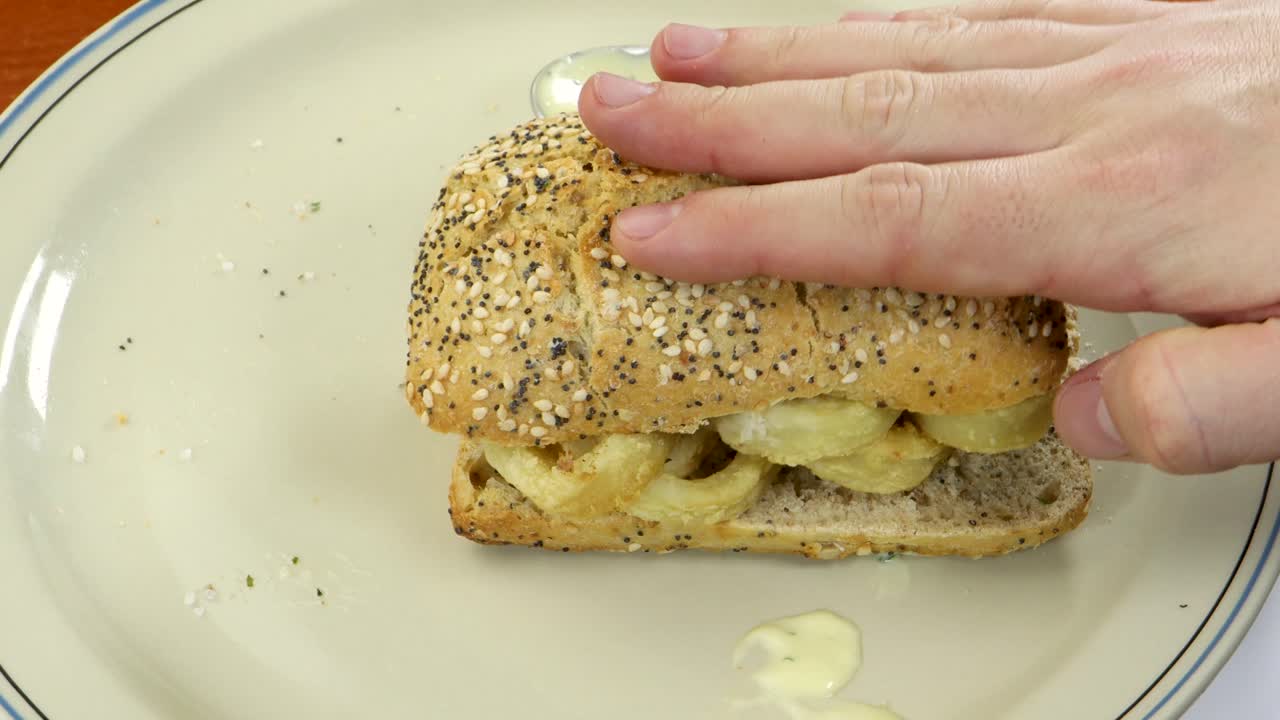Chiudendo un panino con calamari fritti e pane ai cereali