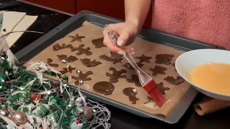 brushing egg wash on gingerbread christmas cookies - isolated