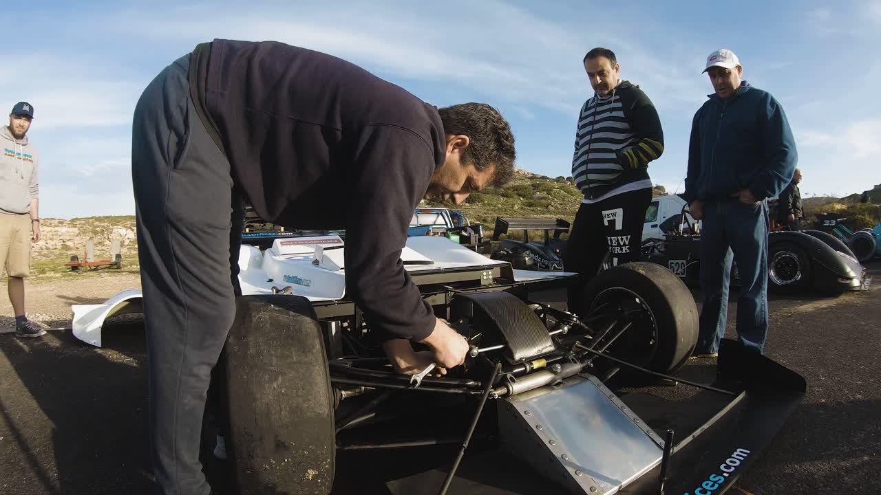 Mechanic Holding A Wrench While Fixing The Engine Of A Racing Car At The Roadside On The Hill In Imtahleb Malta - Panoramic GoPro Shot