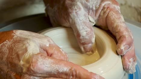 close up of the potter's hand shaping and molding clay on a turning wheel