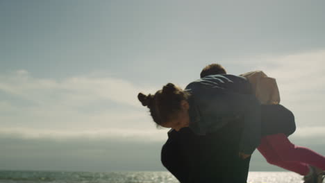 Happy-dad-carry-kid-at-sea-beach.-Parent-child-playing-spinning-around-outside.