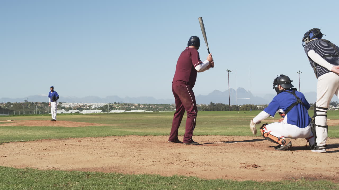 Playing baseball, batter in maroon uniform preparing to hit pitch on field