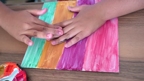 Daughter-doing-her-paint-art-at-home-finalizing-her-job-by-making-a-hand-print-in-the-center