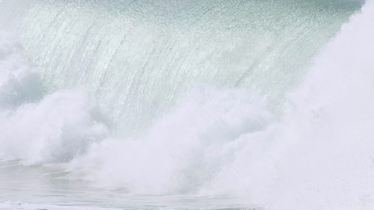 A surfer skillfully maneuvers through a towering wave before it crashes into white foam.