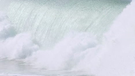 a surfer skillfully maneuvers through a towering wave before it crashes into white foam.