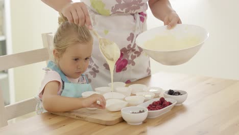 padre vertiendo la masa de muffin en los soportes